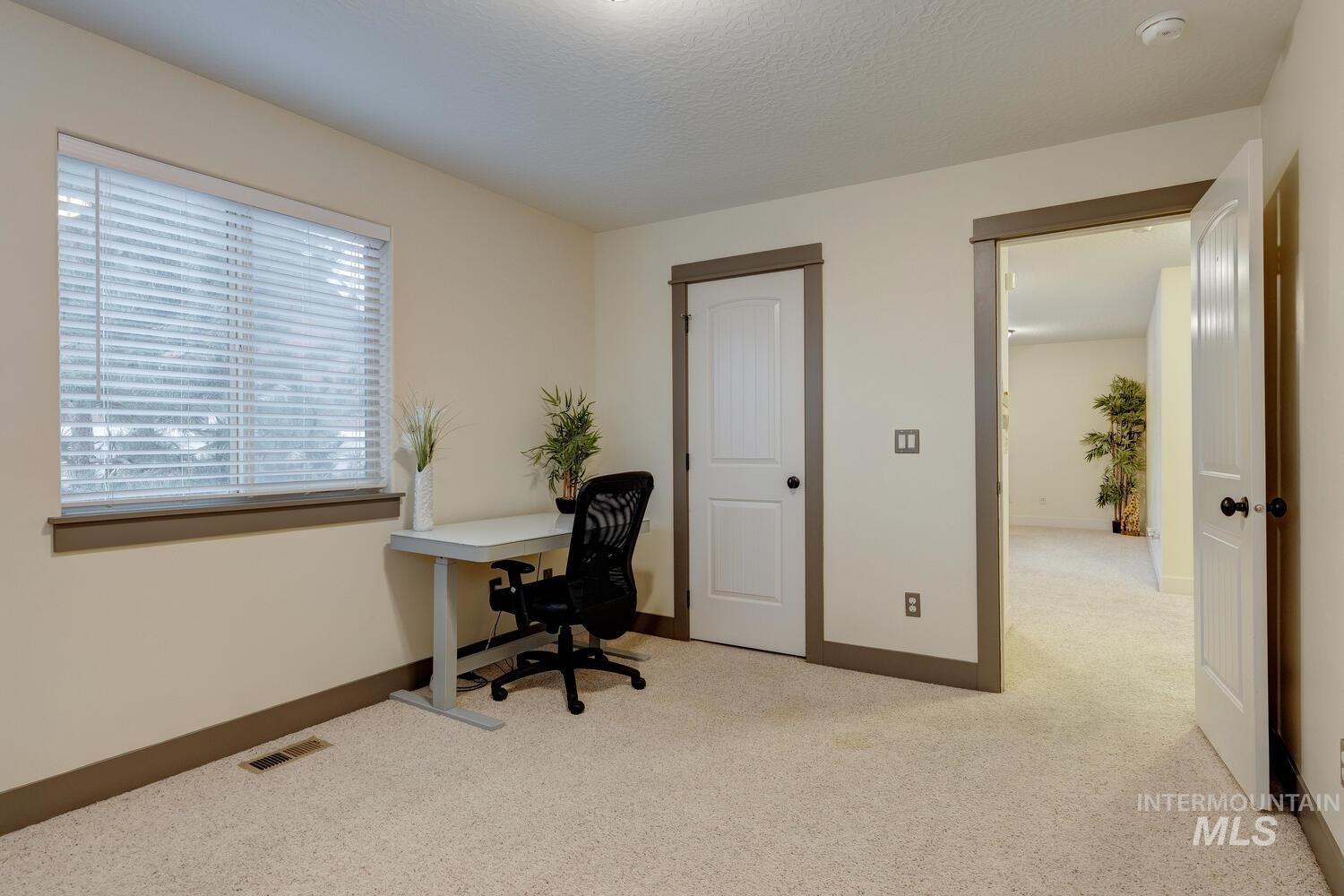 Office area featuring light colored carpet and a textured ceiling