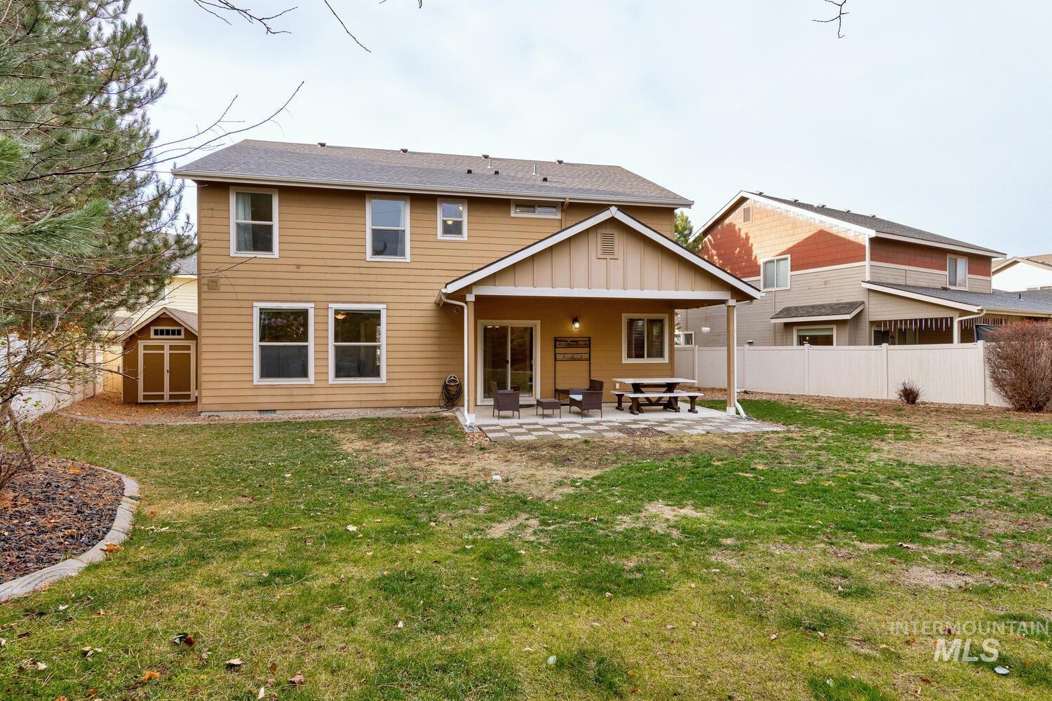 Back of house with a patio, board and batten siding, and a storage shed