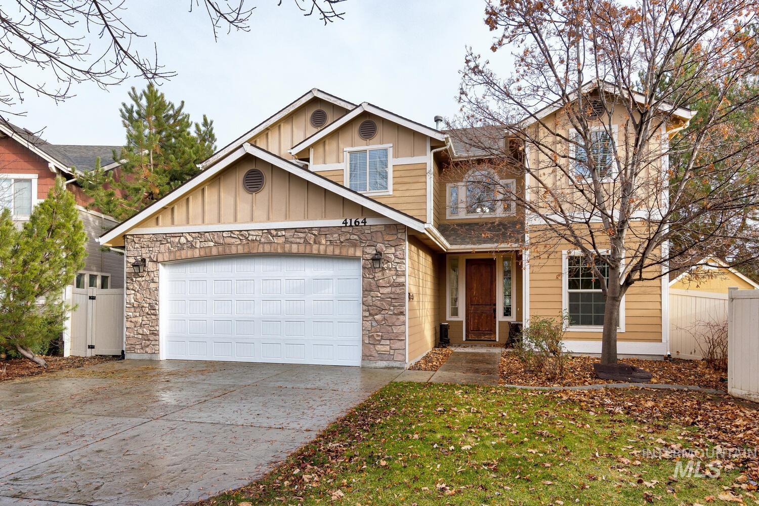 Craftsman-style home with stone siding, board and batten siding, driveway, and an attached garage