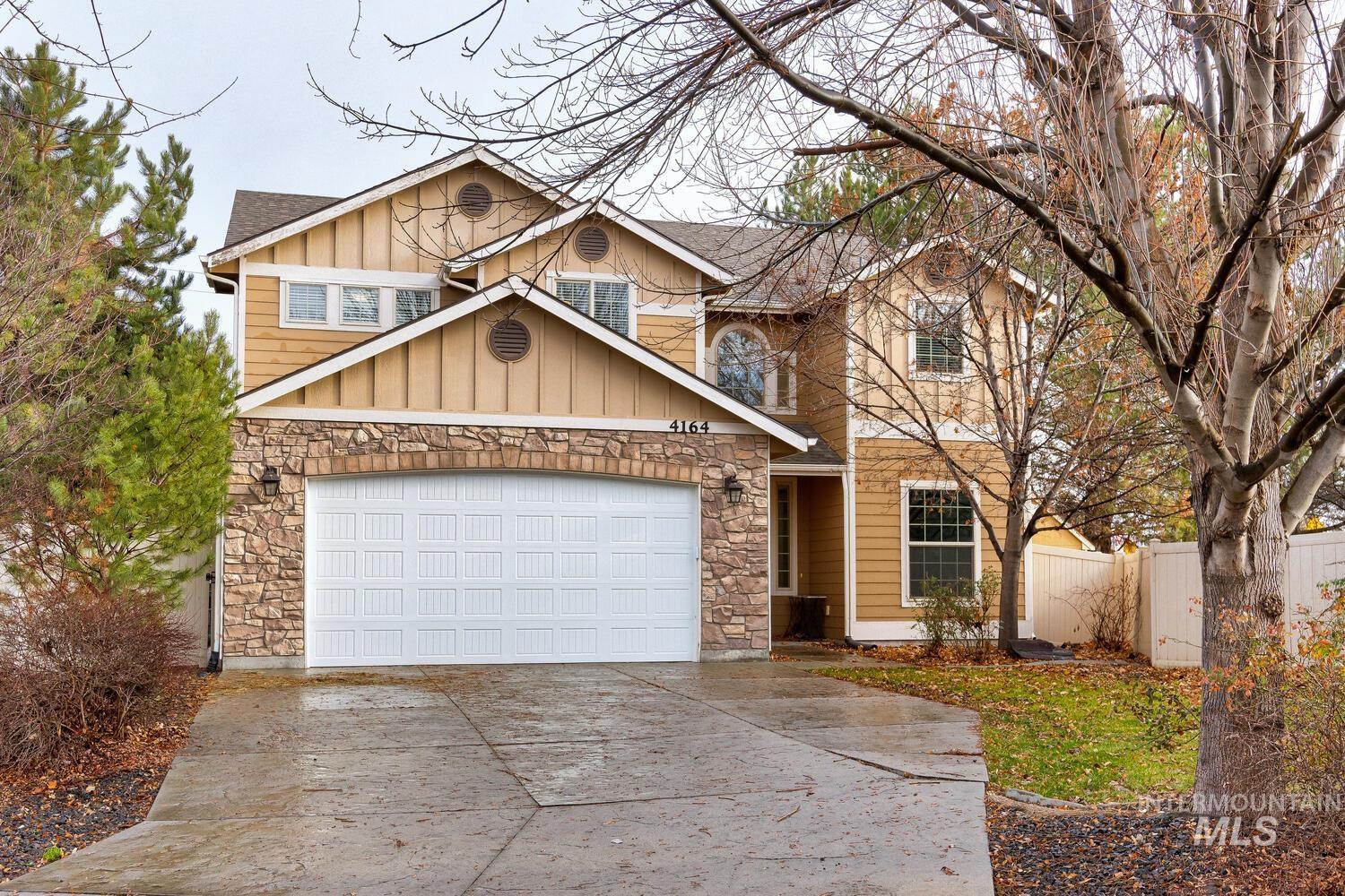 View of front of house with stone siding, driveway, board and batten siding, and a shingled roof