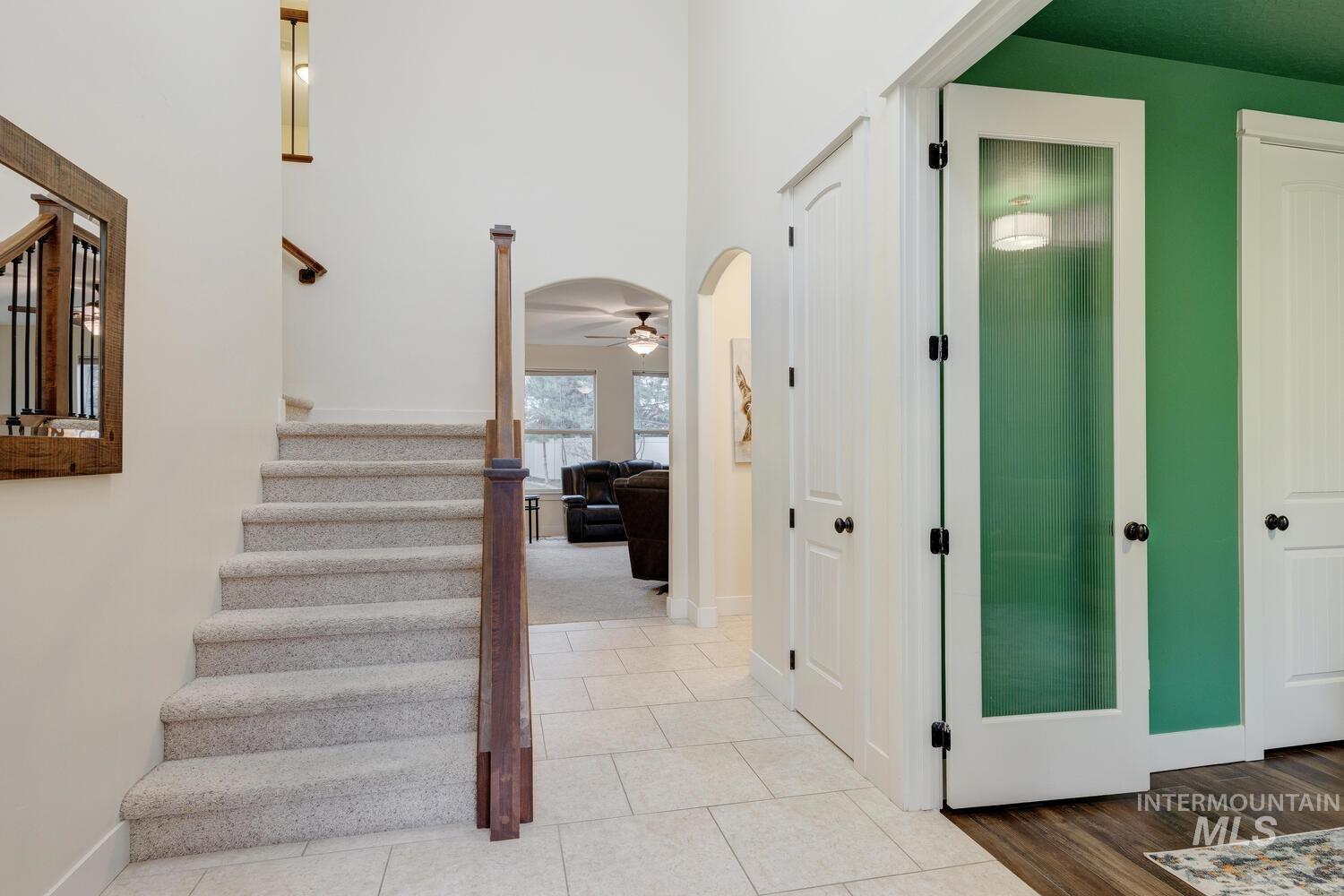 Stairs with arched walkways, tile patterned floors, a towering ceiling, and ceiling fan