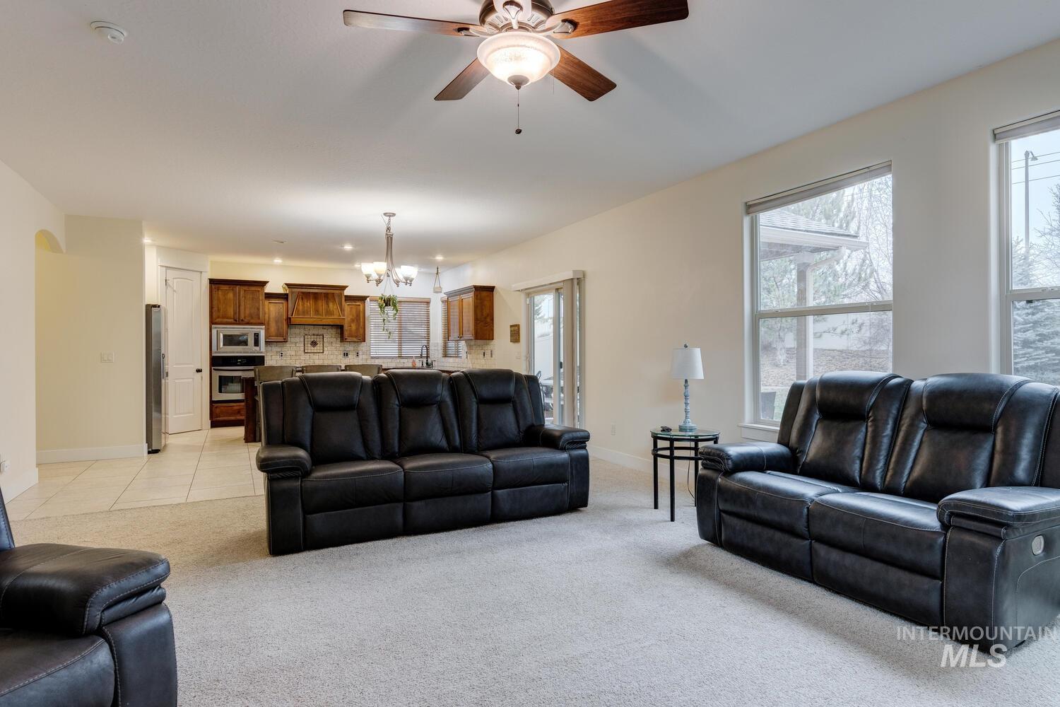 Living area with light carpet, a chandelier, a ceiling fan, and arched walkways