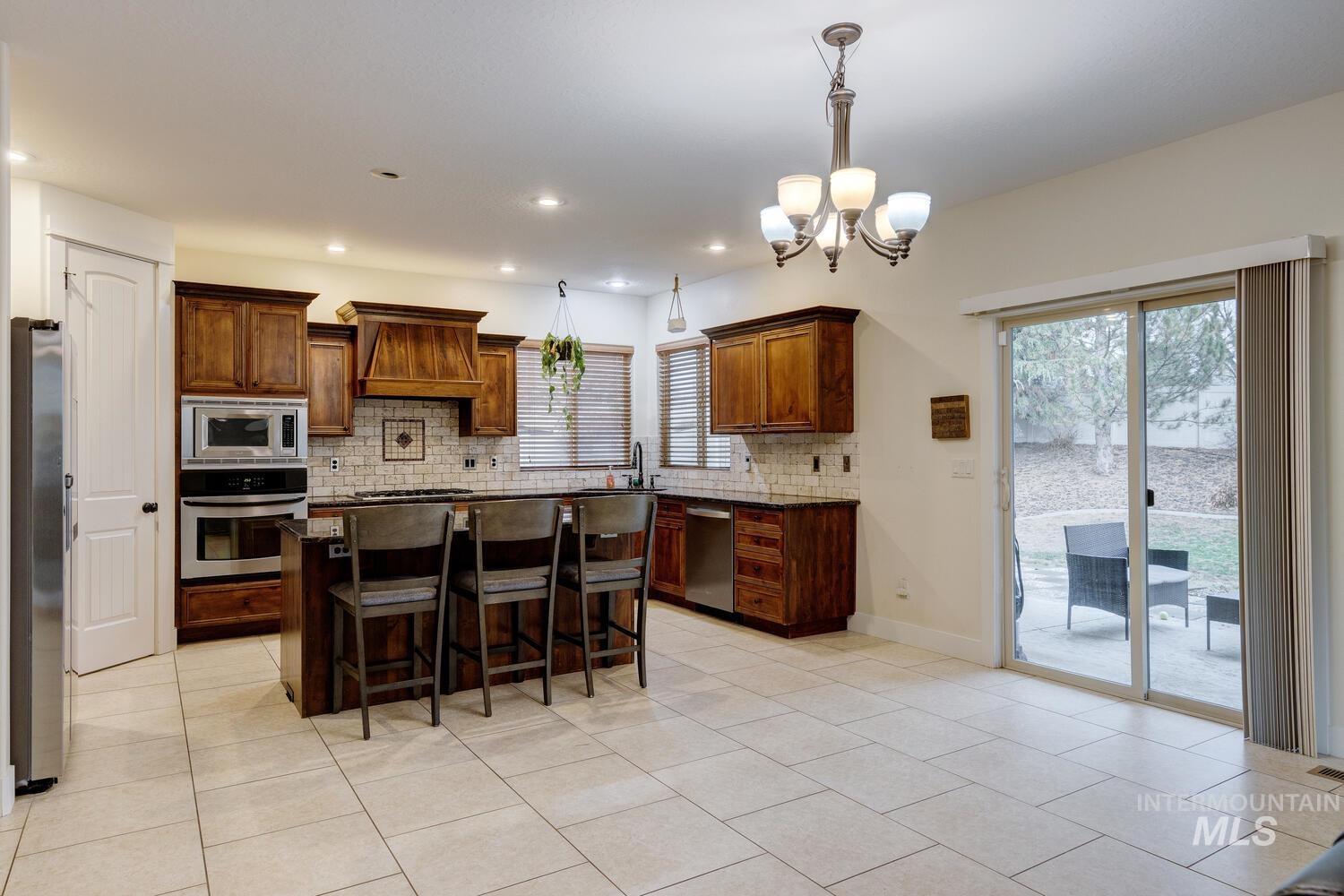 Kitchen featuring a kitchen breakfast bar, a kitchen island, appliances with stainless steel finishes, pendant lighting, and backsplash