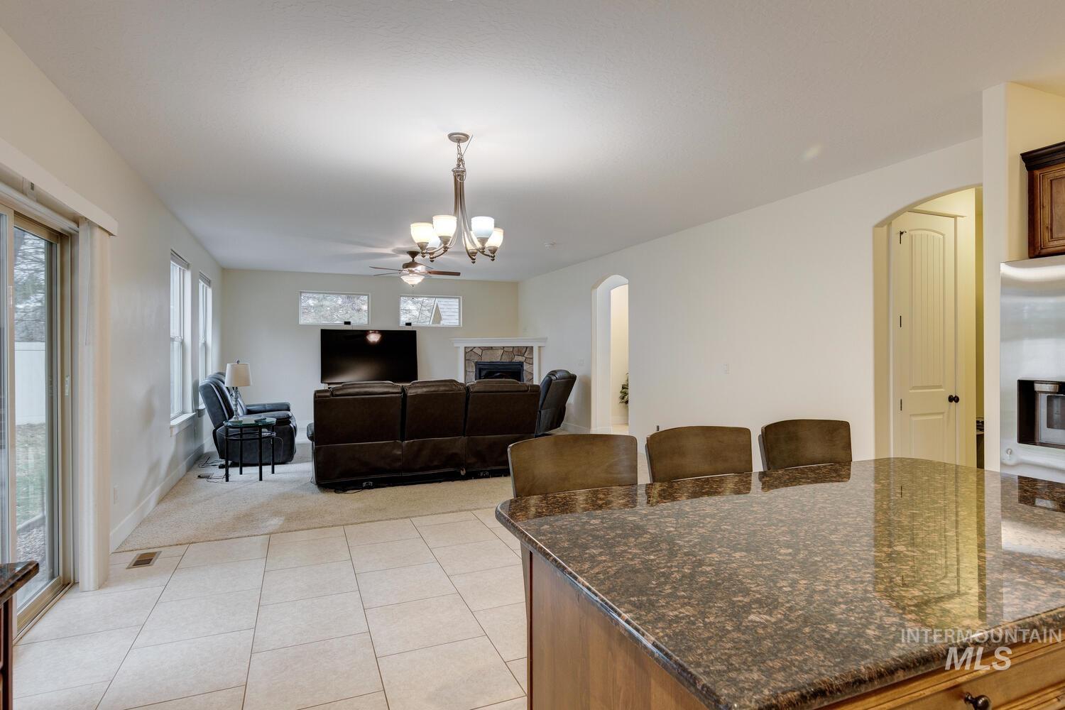 Kitchen with a stone fireplace, dark stone counters, arched walkways, a breakfast bar area, and pendant lighting