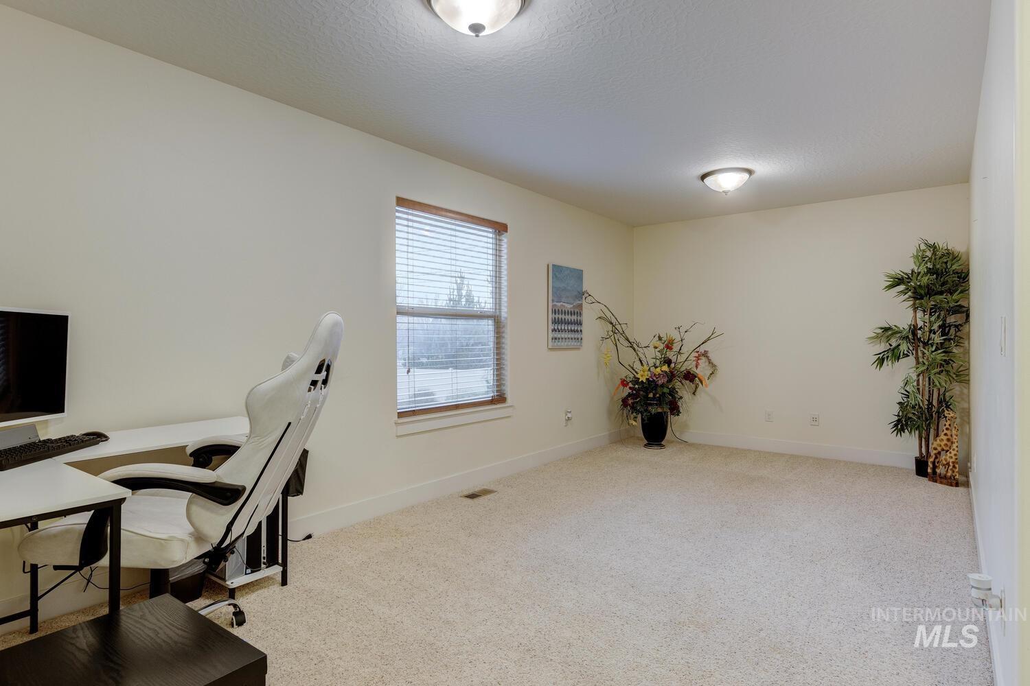 Office area featuring light colored carpet and a textured ceiling