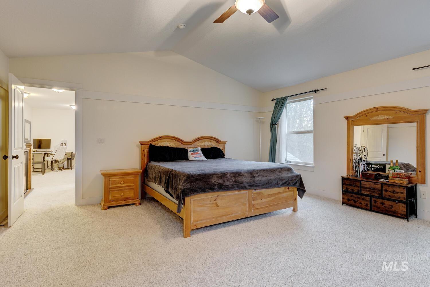 Bedroom with lofted ceiling, carpet floors, and a ceiling fan