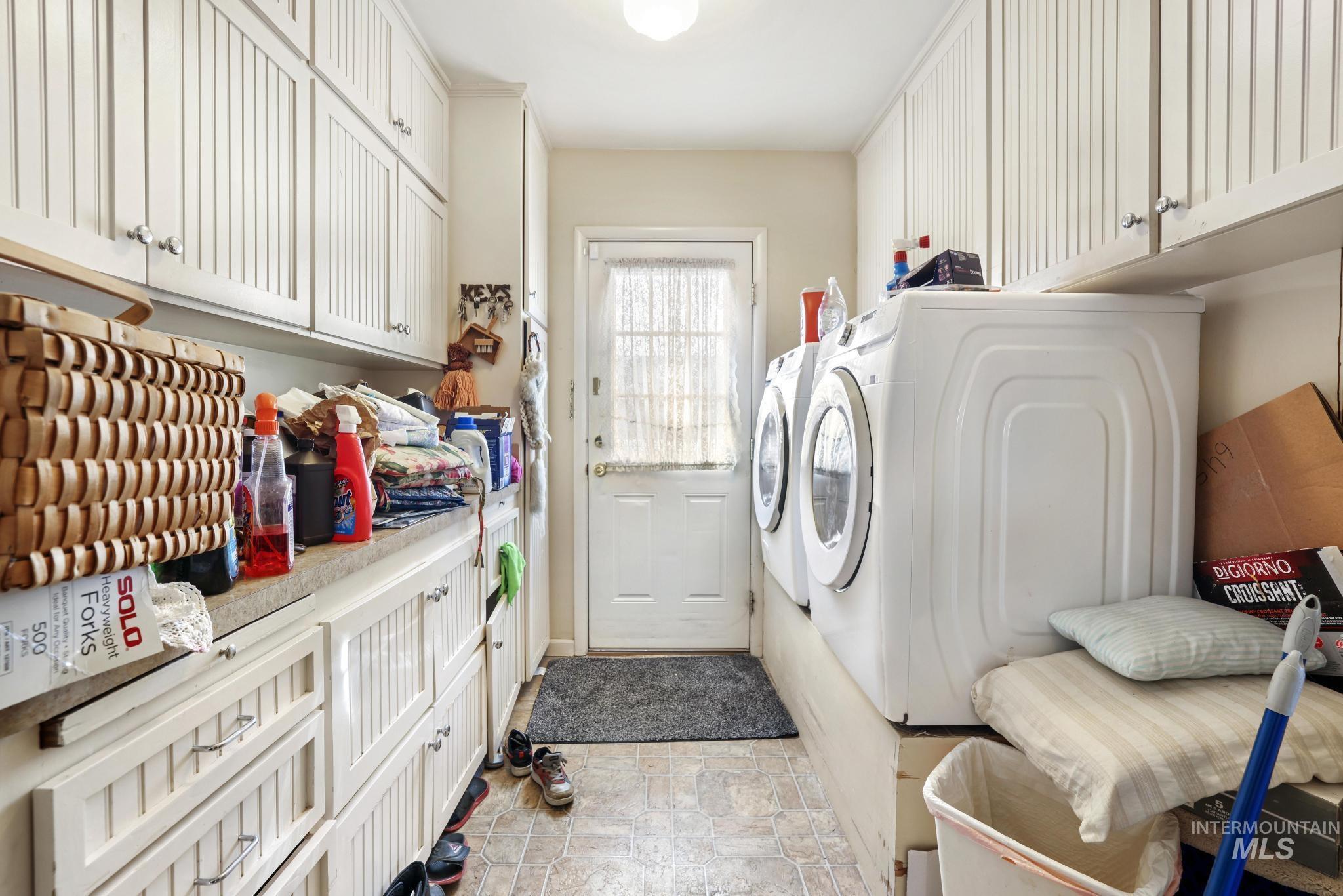 Washroom with cabinet space, washing machine and dryer, and stone finish floors