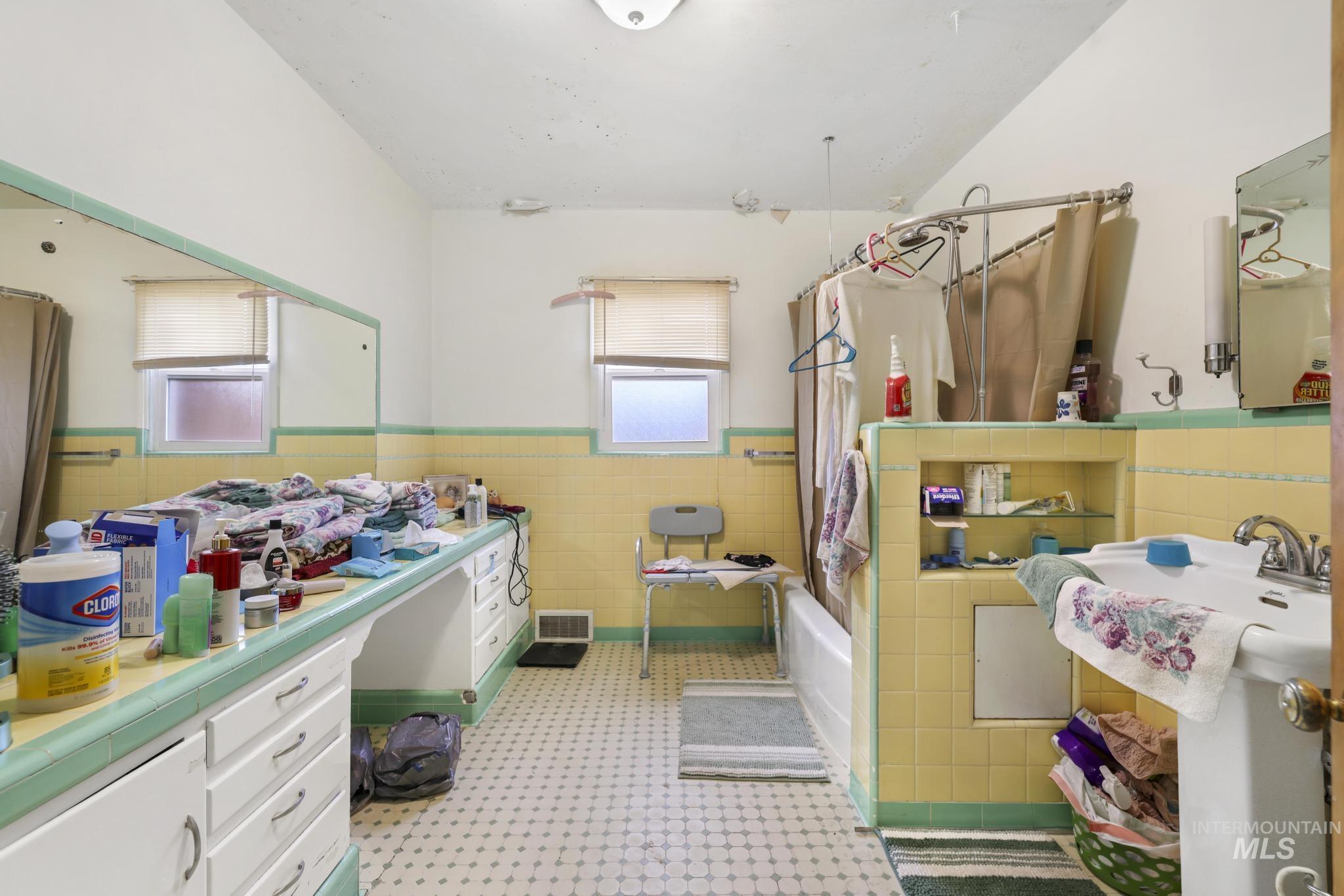Bathroom featuring wainscoting, tile walls, shower / tub combo, vanity, and light flooring