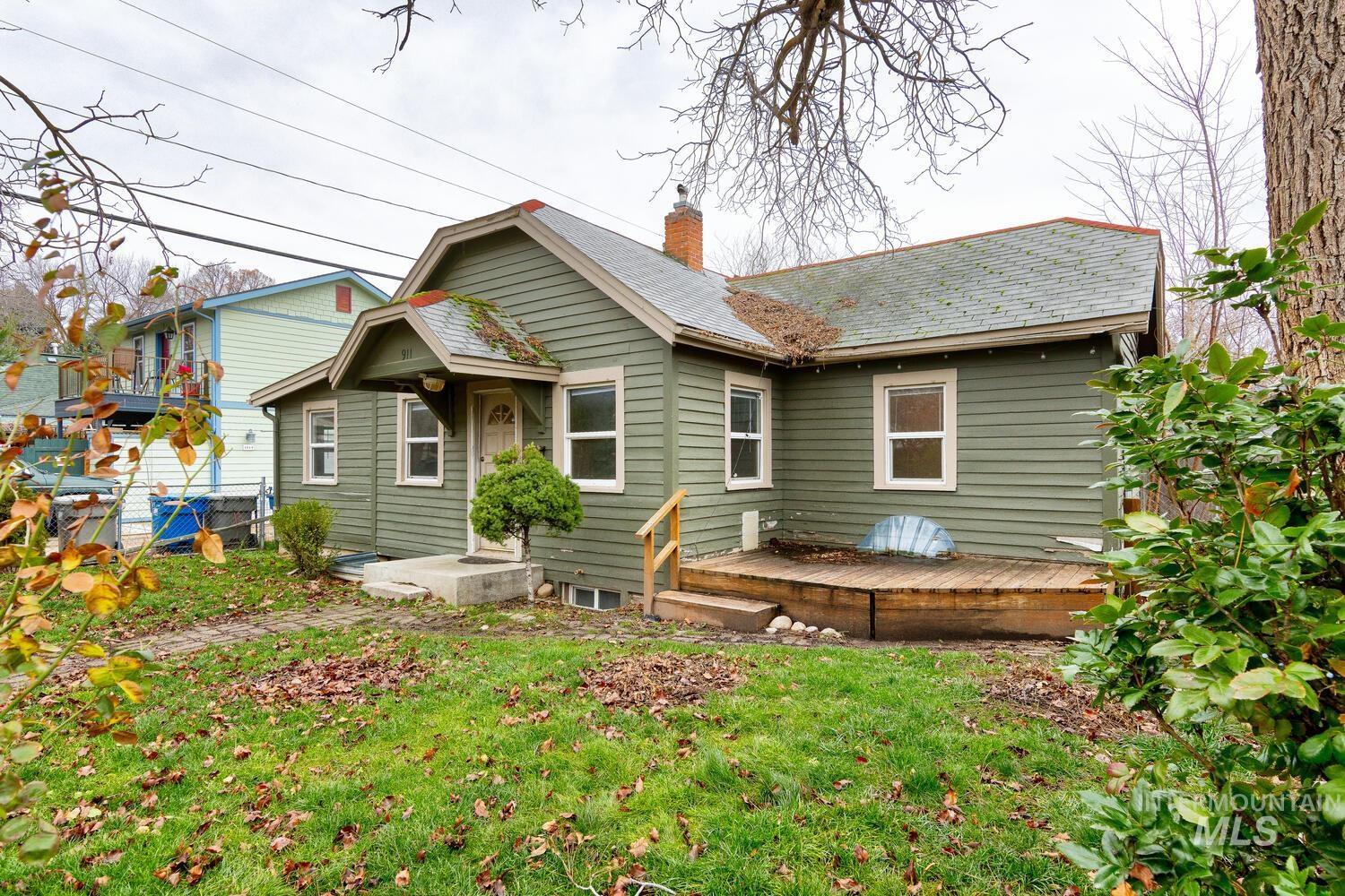 Back of property with a lawn, a wooden deck, and a chimney