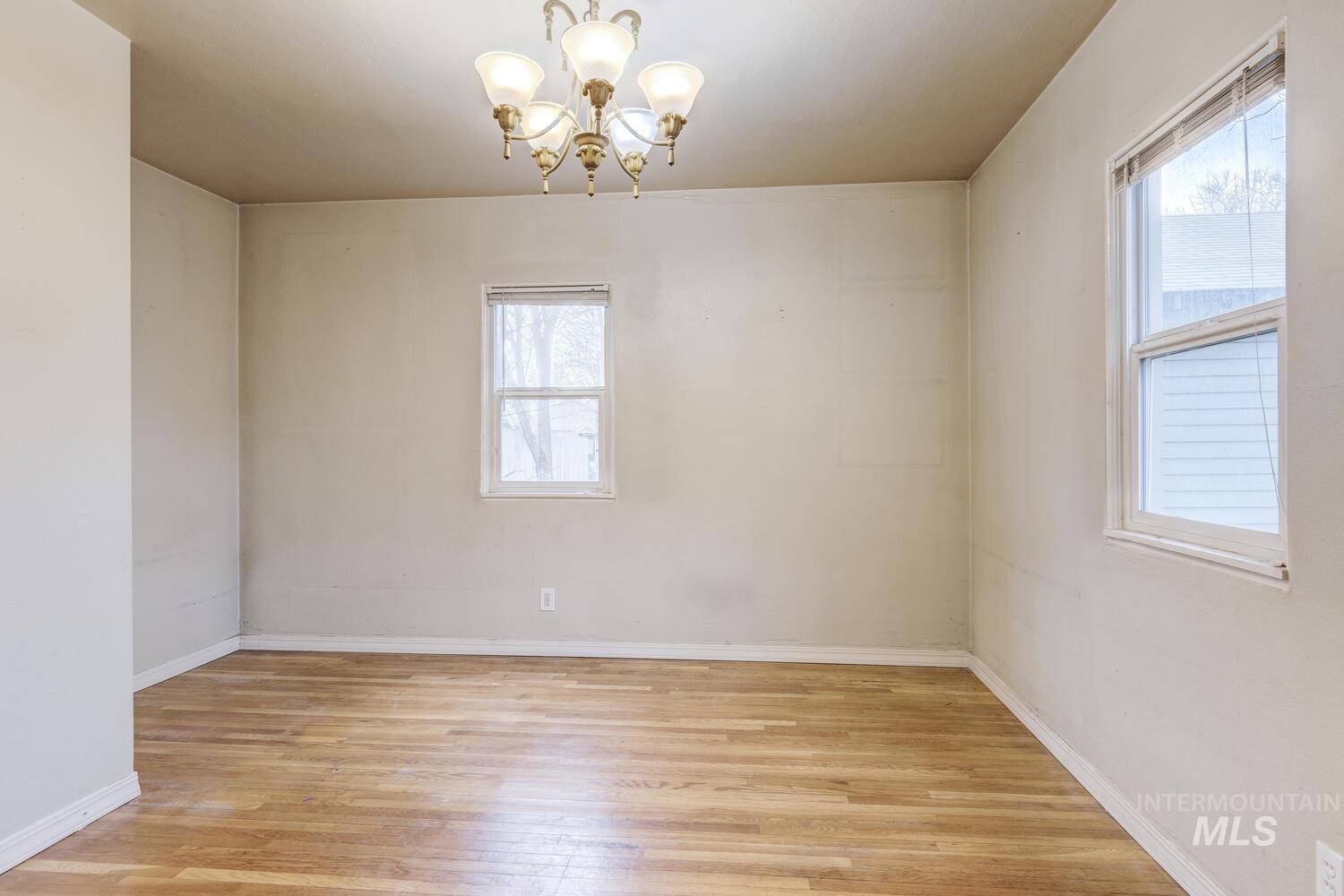 Spare room with light wood-style floors and a chandelier