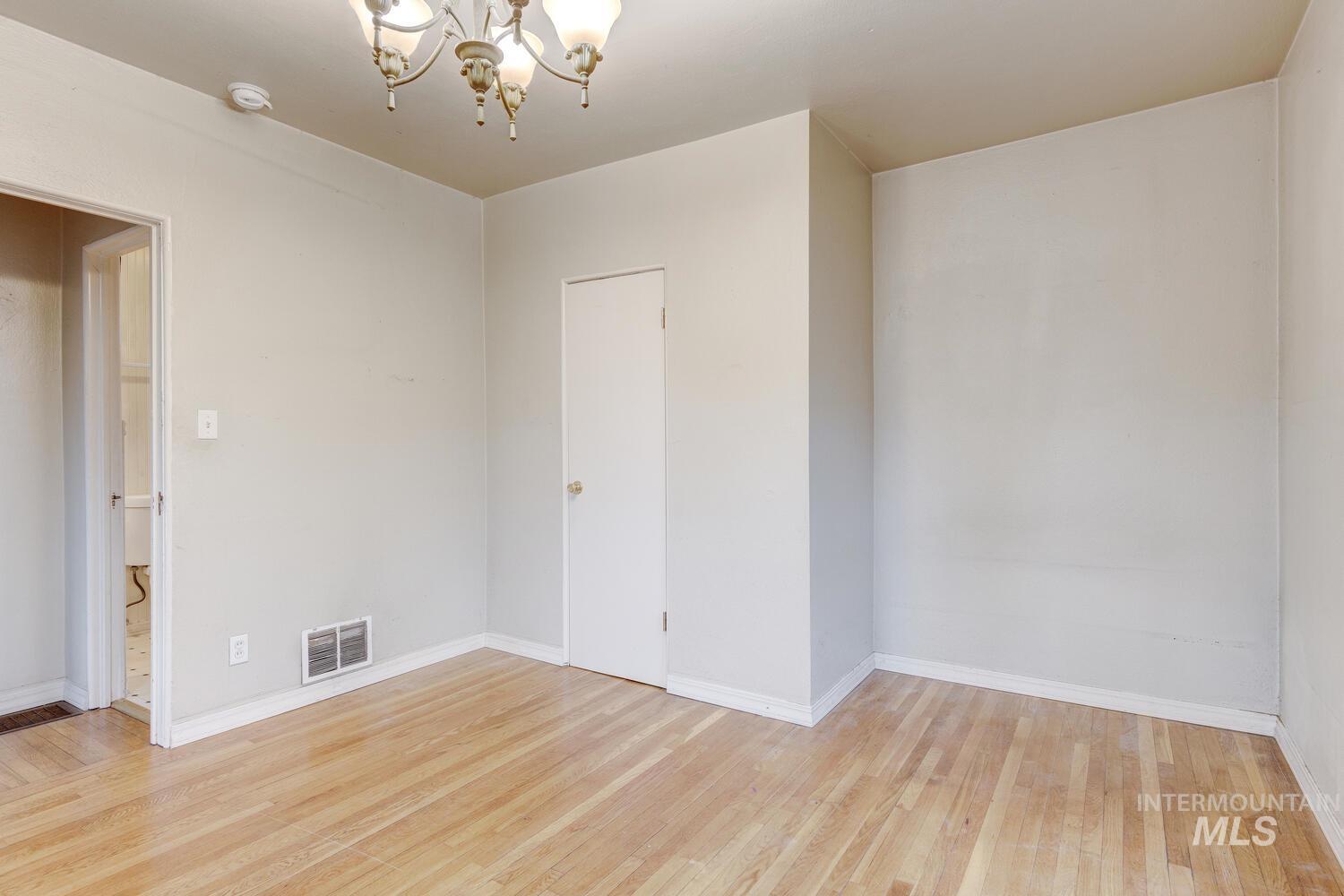 Empty room with a chandelier and light wood-style floors