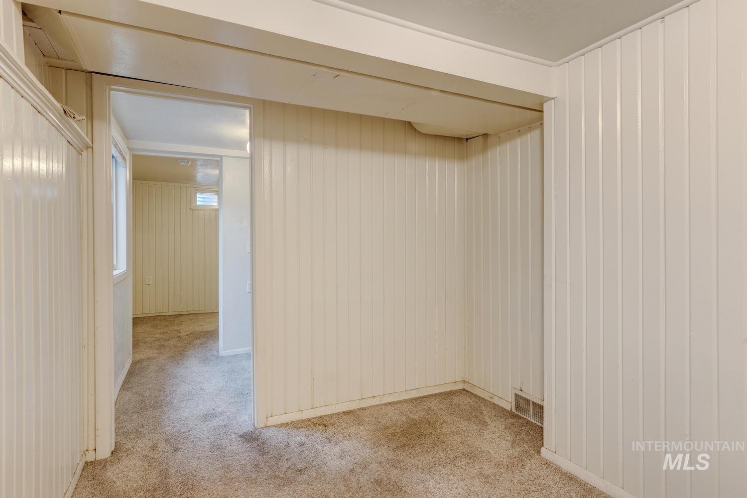 Spare room featuring light carpet and wood walls