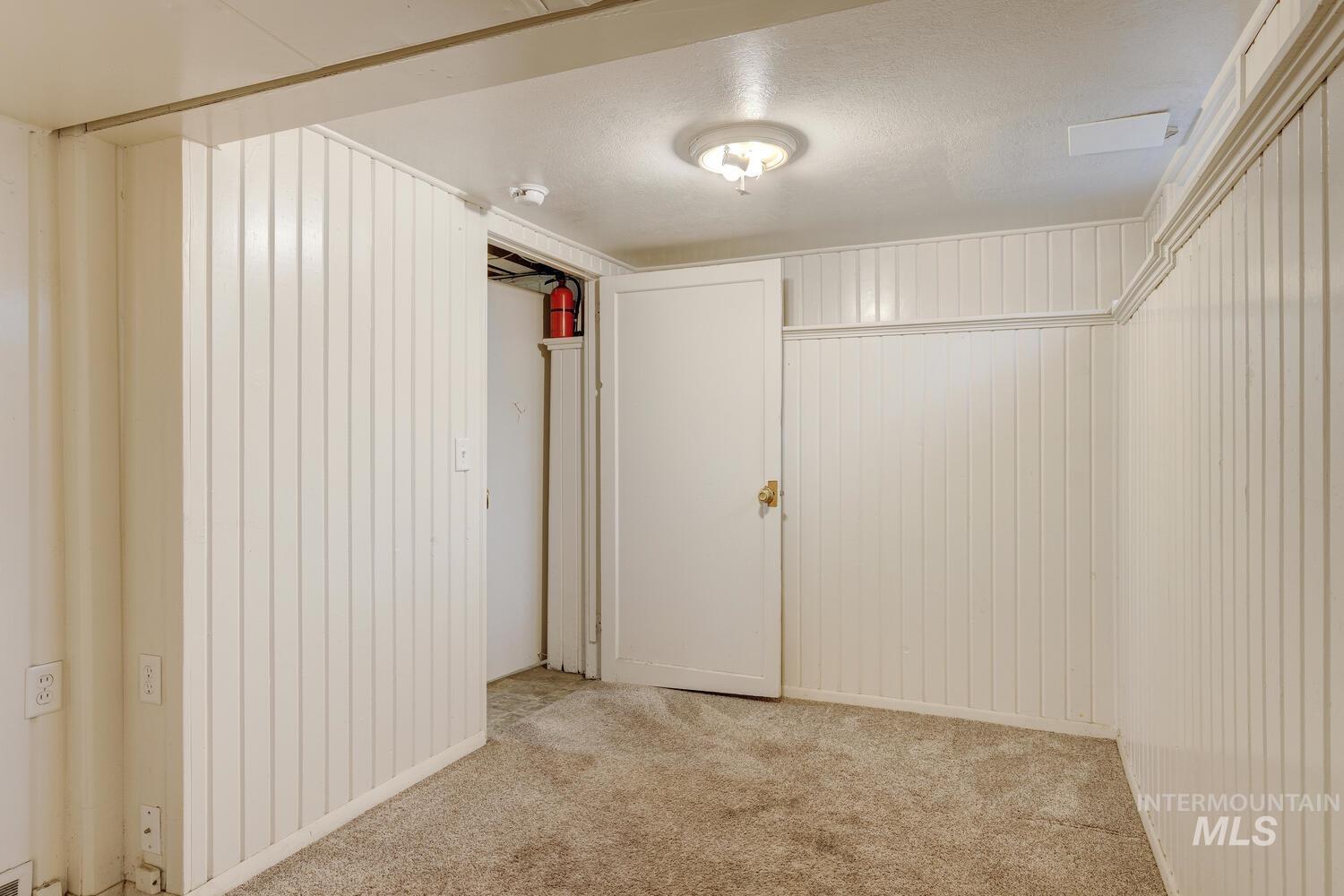 Unfurnished bedroom featuring carpet, wooden walls, and a textured ceiling