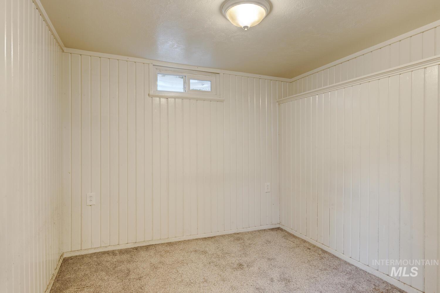Carpeted spare room with wooden walls
