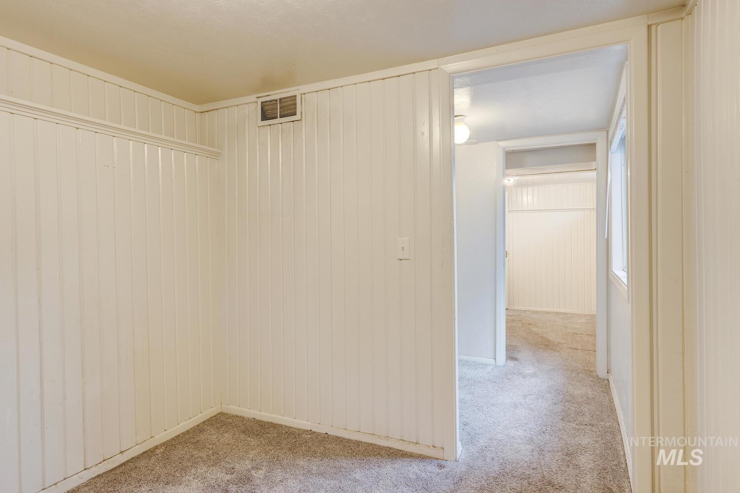 Empty room featuring light colored carpet and wooden walls