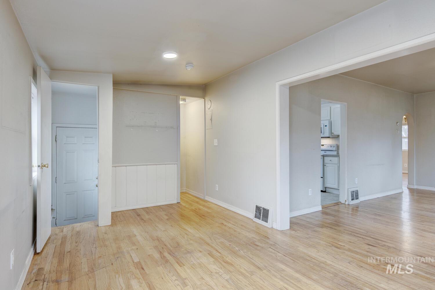 Empty room with light wood-style flooring and arched walkways
