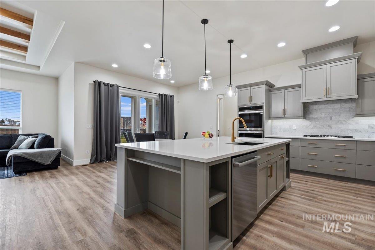 Kitchen featuring gray cabinets, open shelves, open floor plan, hanging light fixtures, and recessed lighting