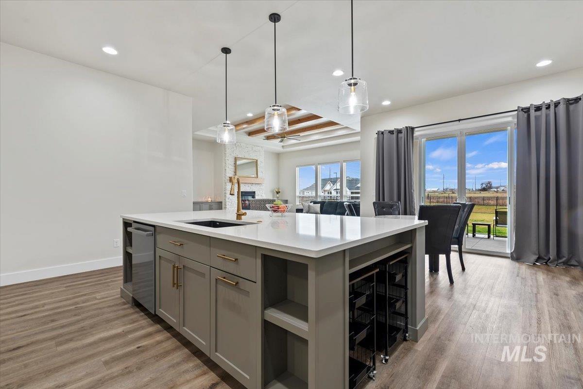 Kitchen featuring gray cabinets, pendant lighting, light wood-type flooring, a kitchen island with sink, and recessed lighting