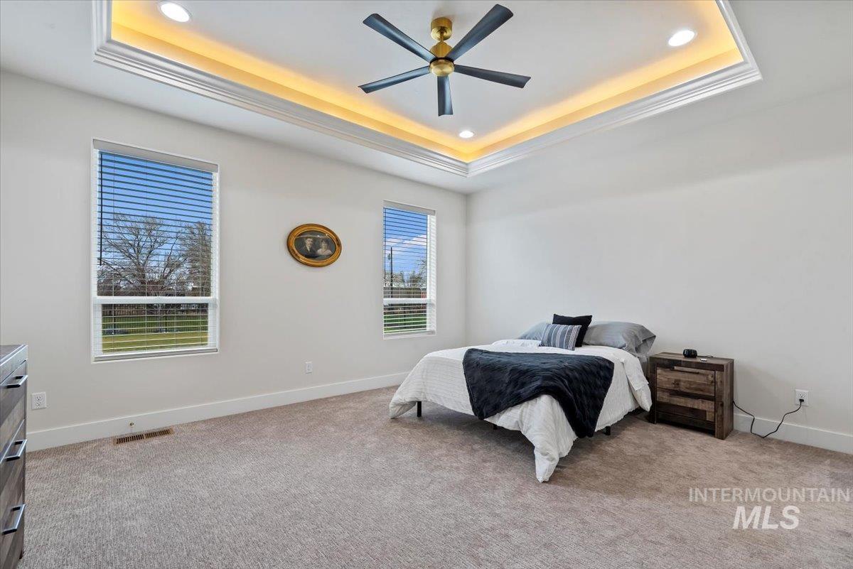 Bedroom featuring recessed lighting, light colored carpet, ceiling fan, and a tray ceiling