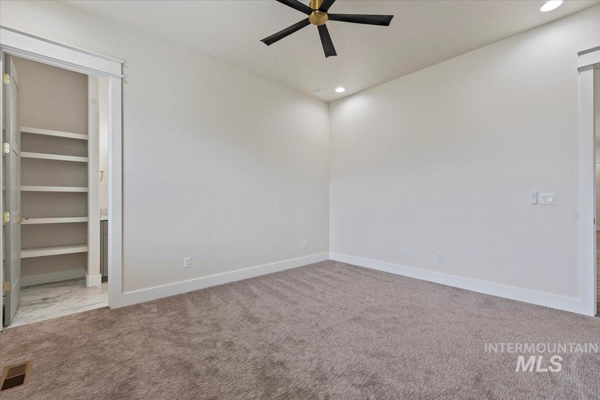 Unfurnished bedroom featuring a spacious closet, recessed lighting, a ceiling fan, and light carpet