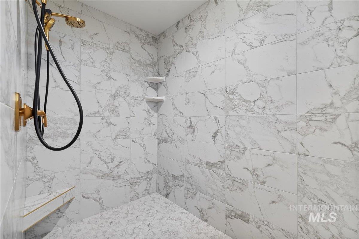 Full bath with a marble finish shower