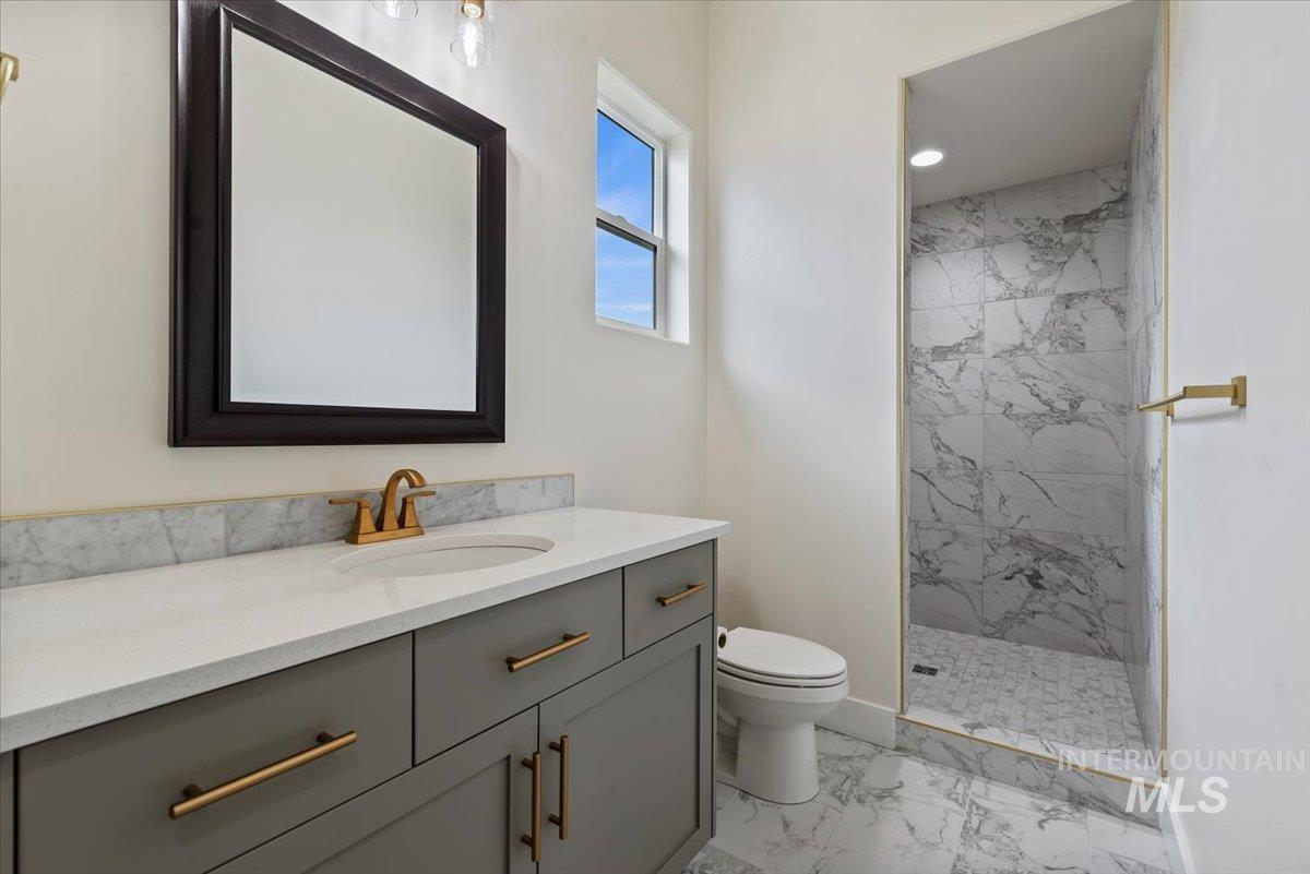 Full bathroom featuring light marble finish flooring, vanity, and a marble finish shower