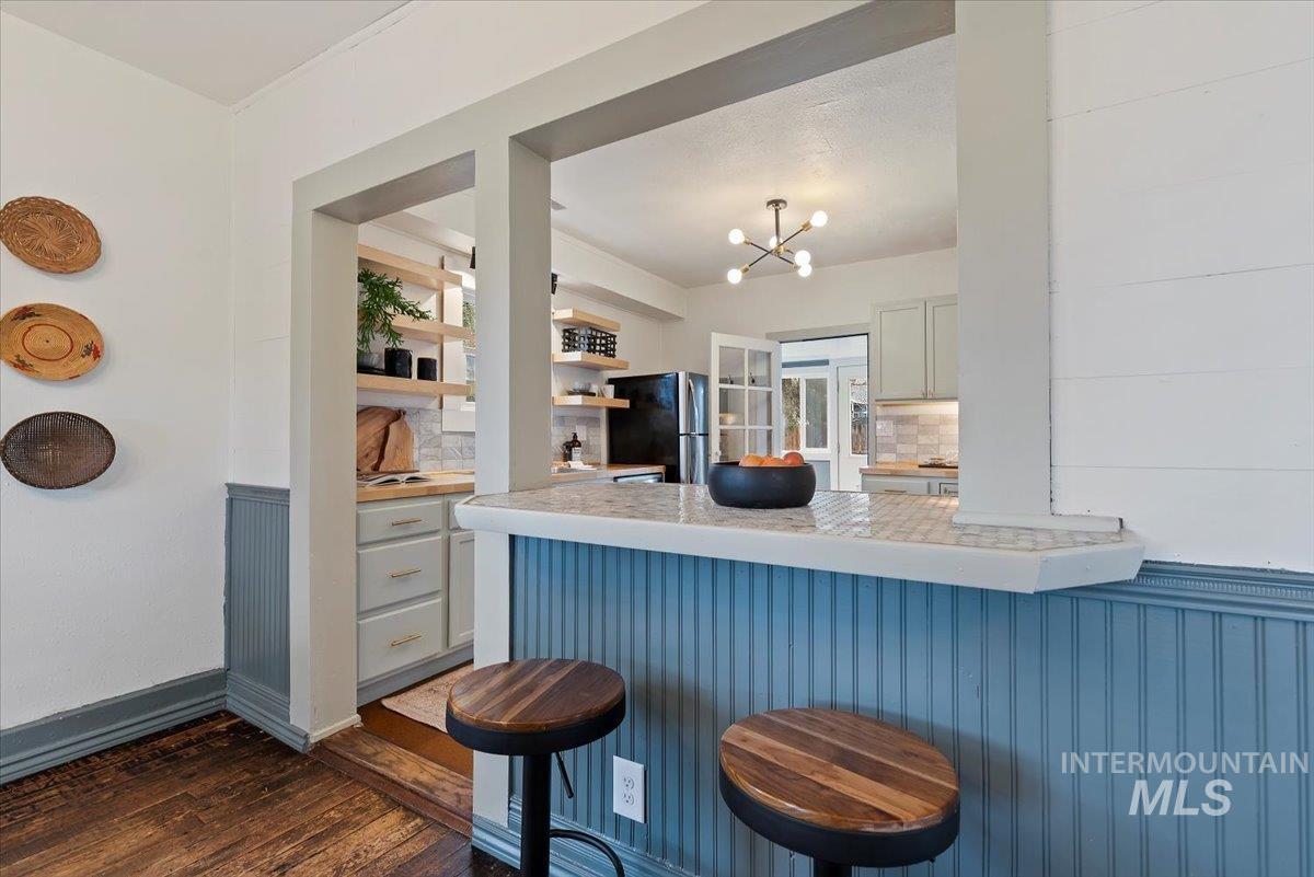 Kitchen featuring light countertops, a kitchen bar, backsplash, and freestanding refrigerator