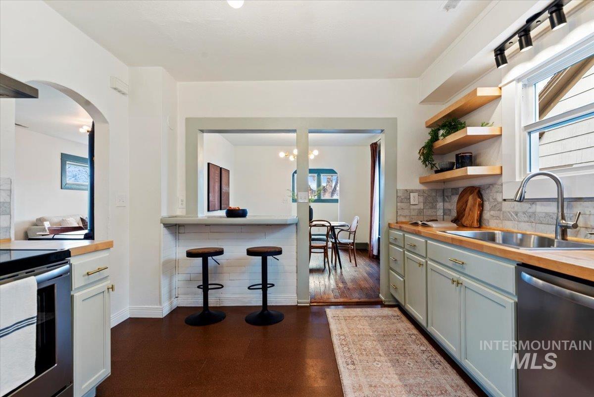 Kitchen featuring dishwasher, black electric range, plenty of natural light, and arched walkways