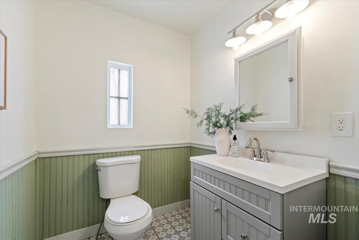 Bathroom with a wainscoted wall, vanity, and light flooring
