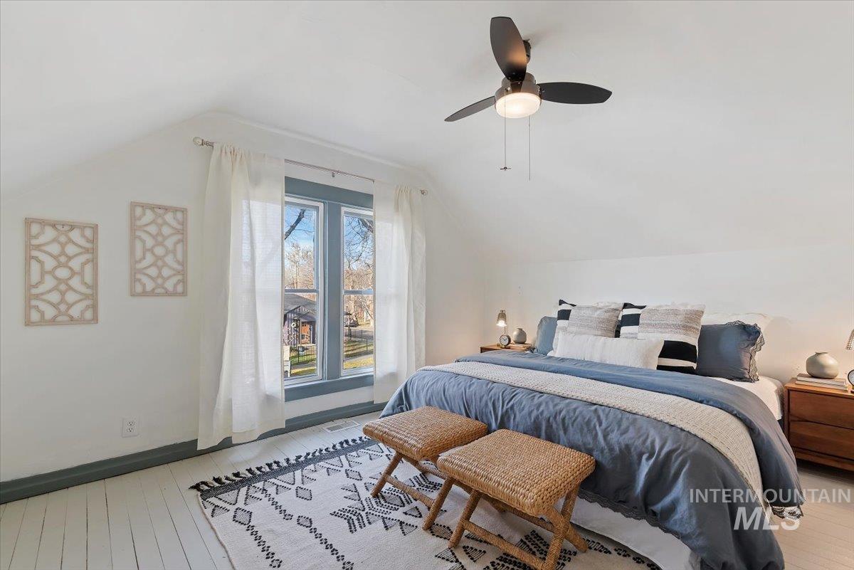 Bedroom with lofted ceiling, light wood-style floors, and a ceiling fan