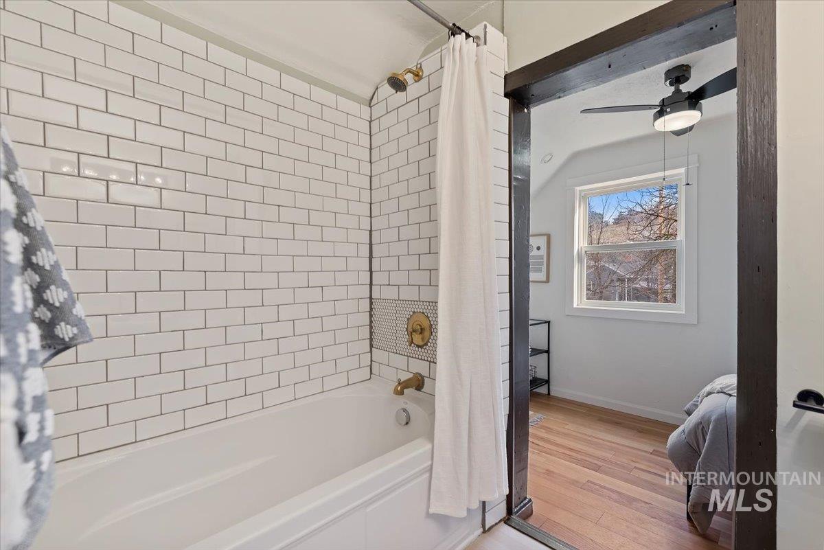 Full bathroom with shower / tub combo, light wood finished floors, and a ceiling fan