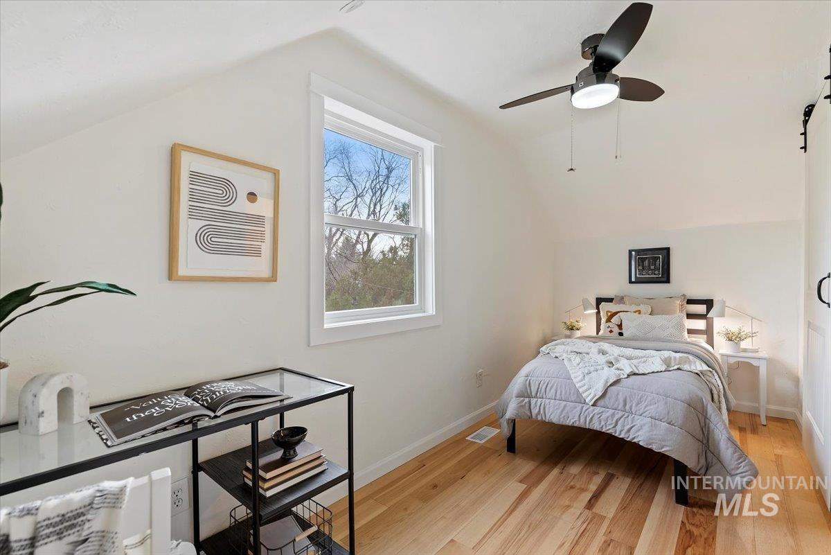 Bedroom with lofted ceiling, light wood finished floors, and ceiling fan
