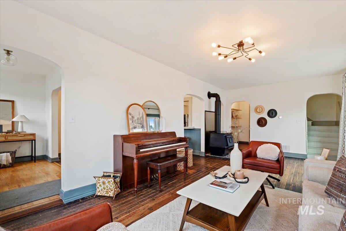 Living room with arched walkways, wood-type flooring, and a wood stove