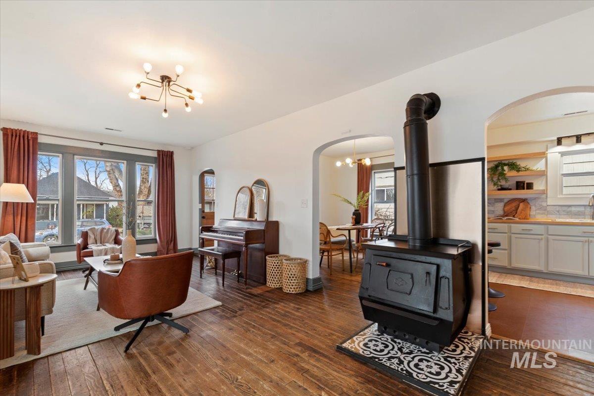 Living room featuring a chandelier, plenty of natural light, arched walkways, and dark wood finished floors