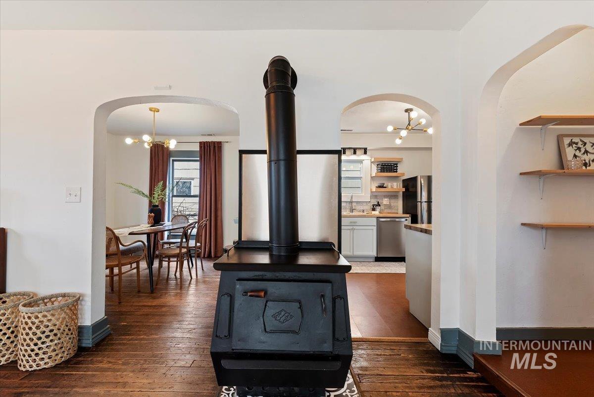 Living room featuring a chandelier, dark wood-style floors, arched walkways, and a wood stove