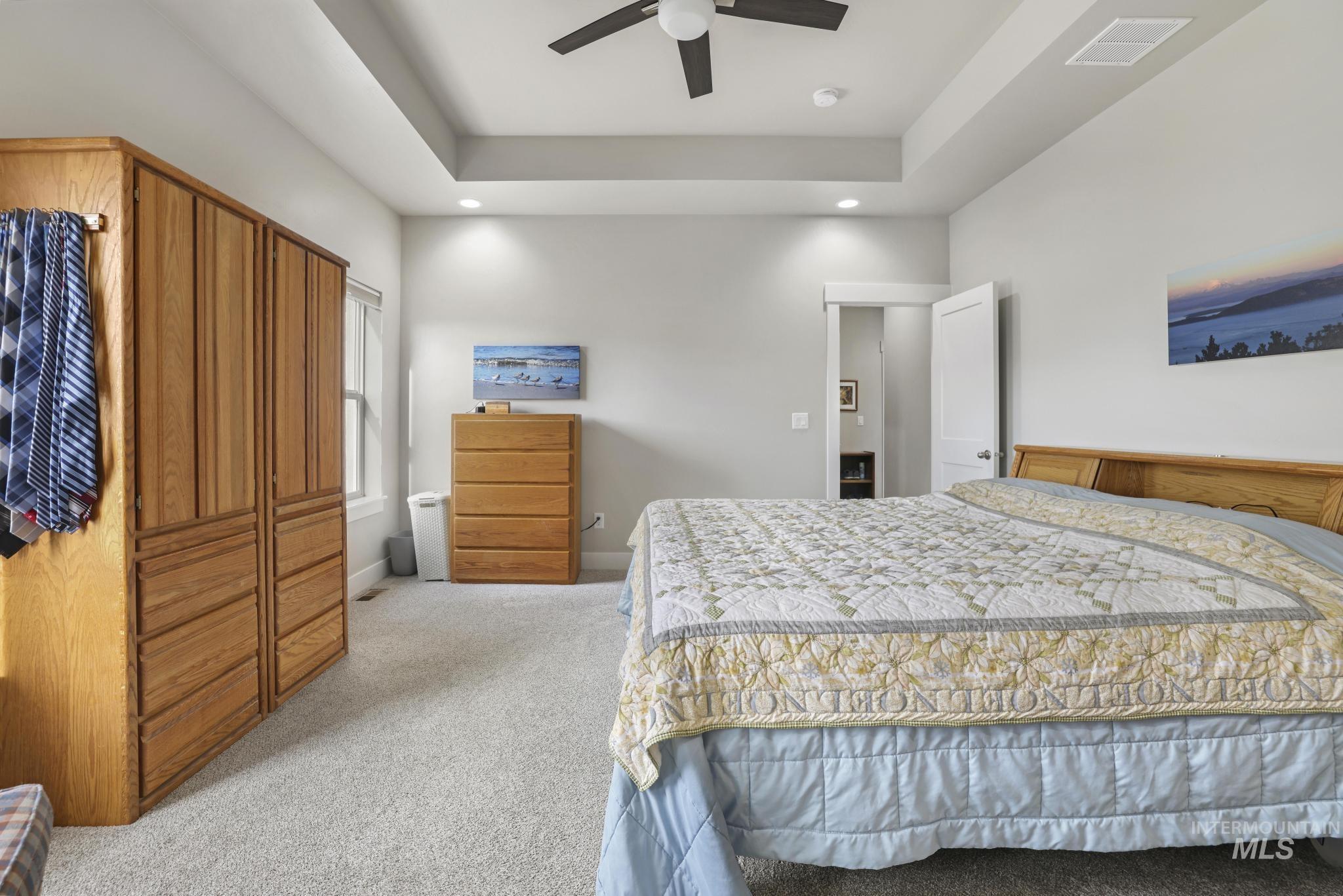 Bedroom featuring light carpet, a raised ceiling, recessed lighting, and ceiling fan