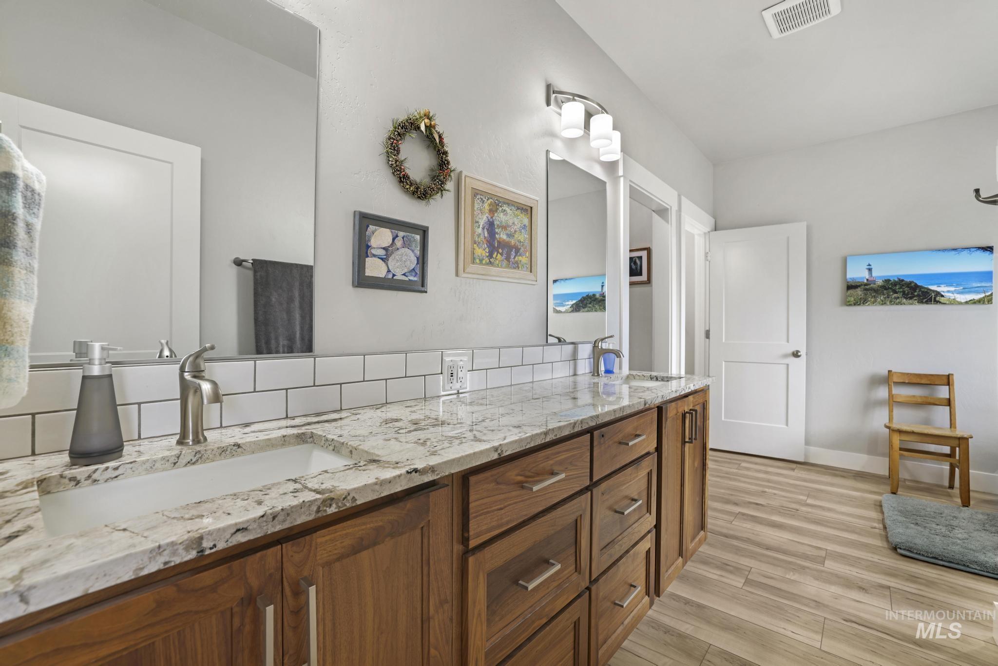 Full bath with double vanity and light wood finished floors