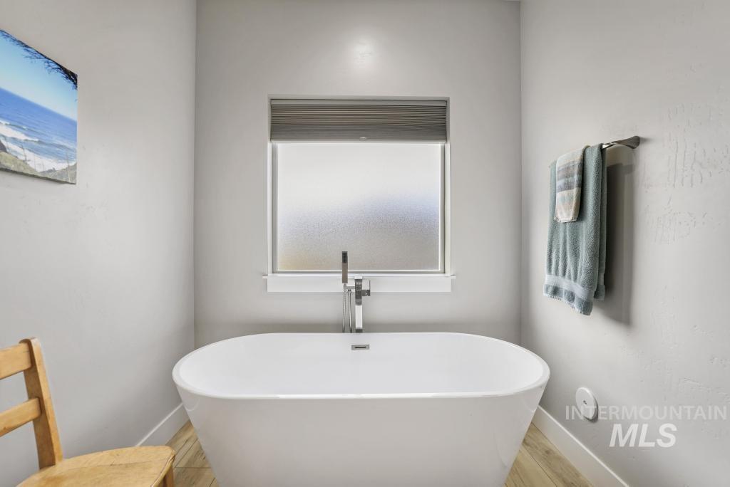 Bathroom featuring a soaking tub and wood finished floors