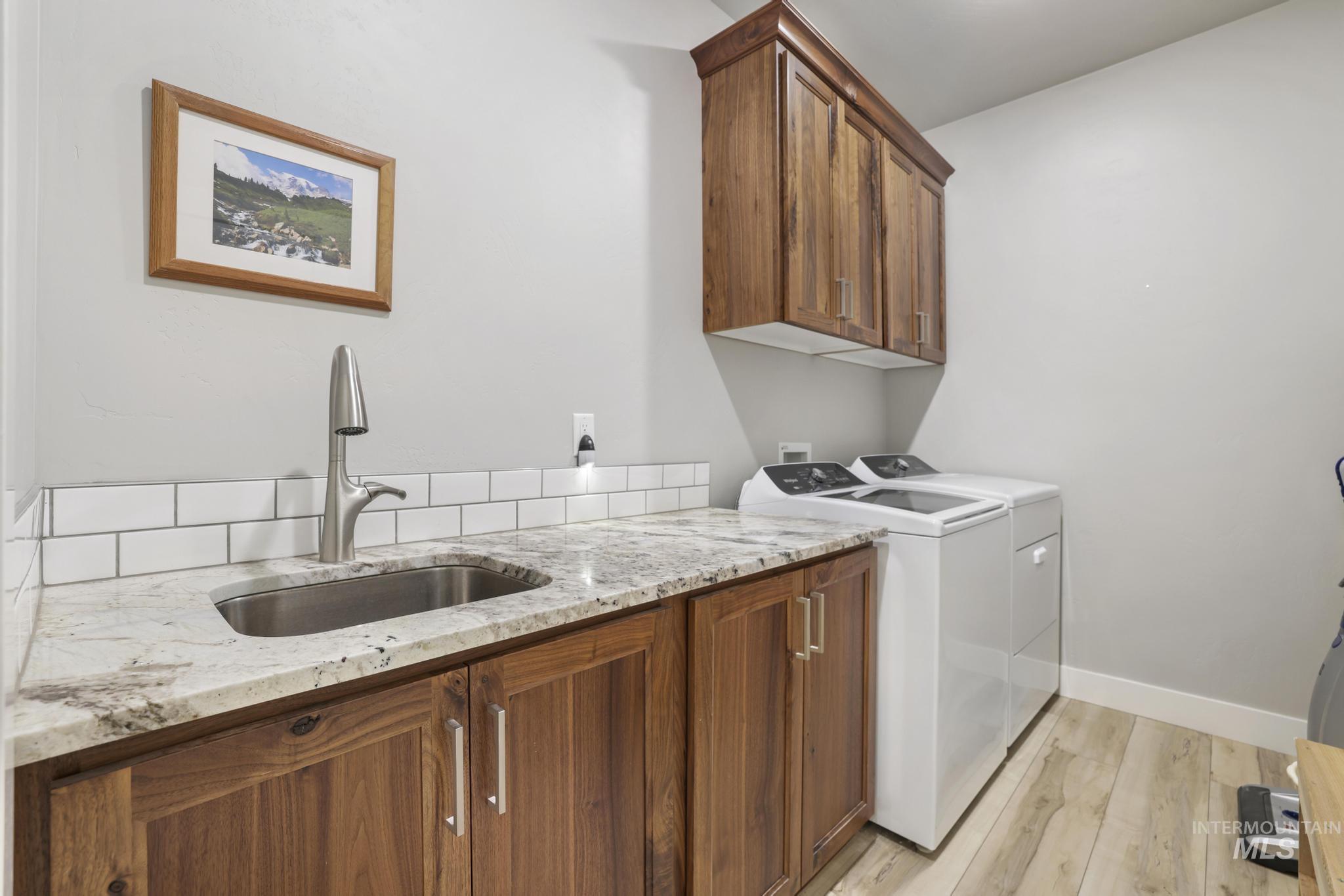 Laundry room featuring cabinet space, washer and dryer, and light wood finished floors