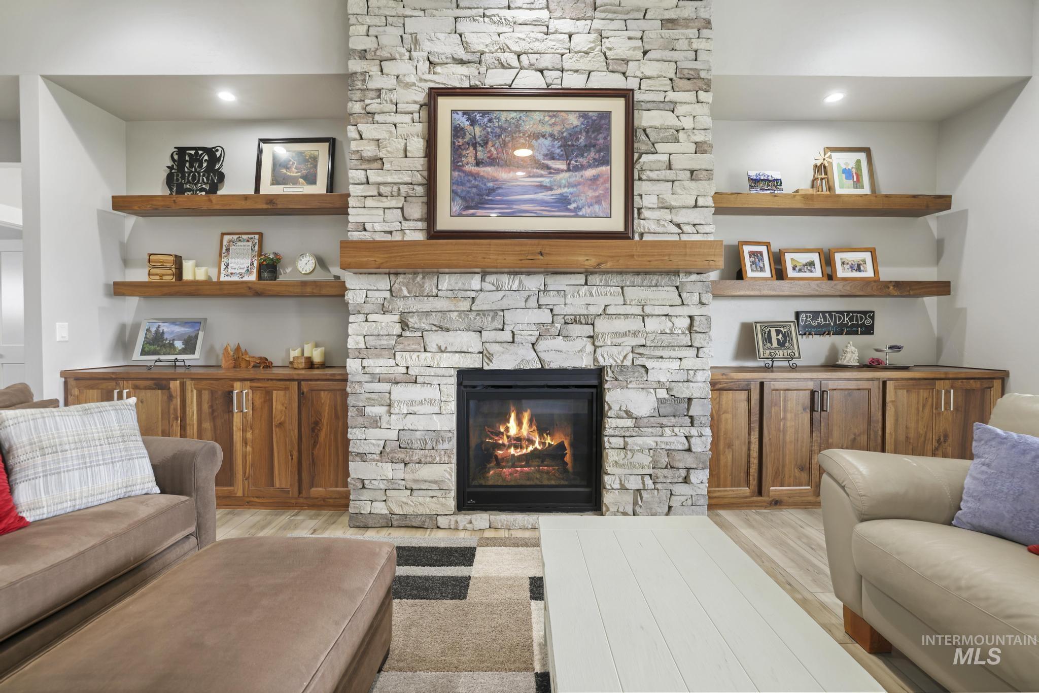 Living room with a stone fireplace, light wood-style flooring, and recessed lighting