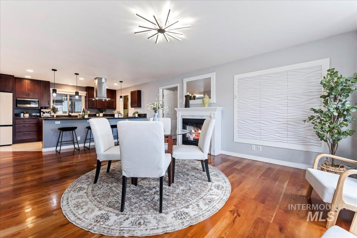 Dining space with dark wood-type flooring and a glass covered fireplace