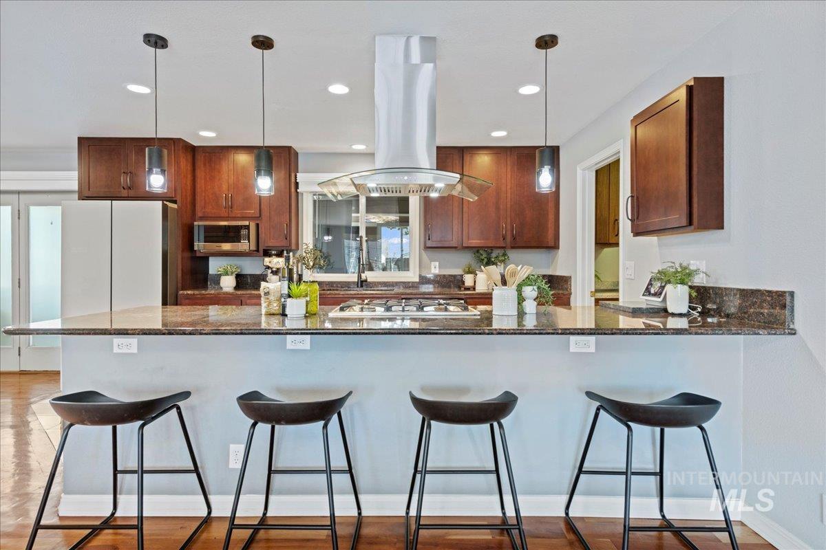 Kitchen with dark stone countertops, decorative light fixtures, a breakfast bar, a peninsula, and recessed lighting