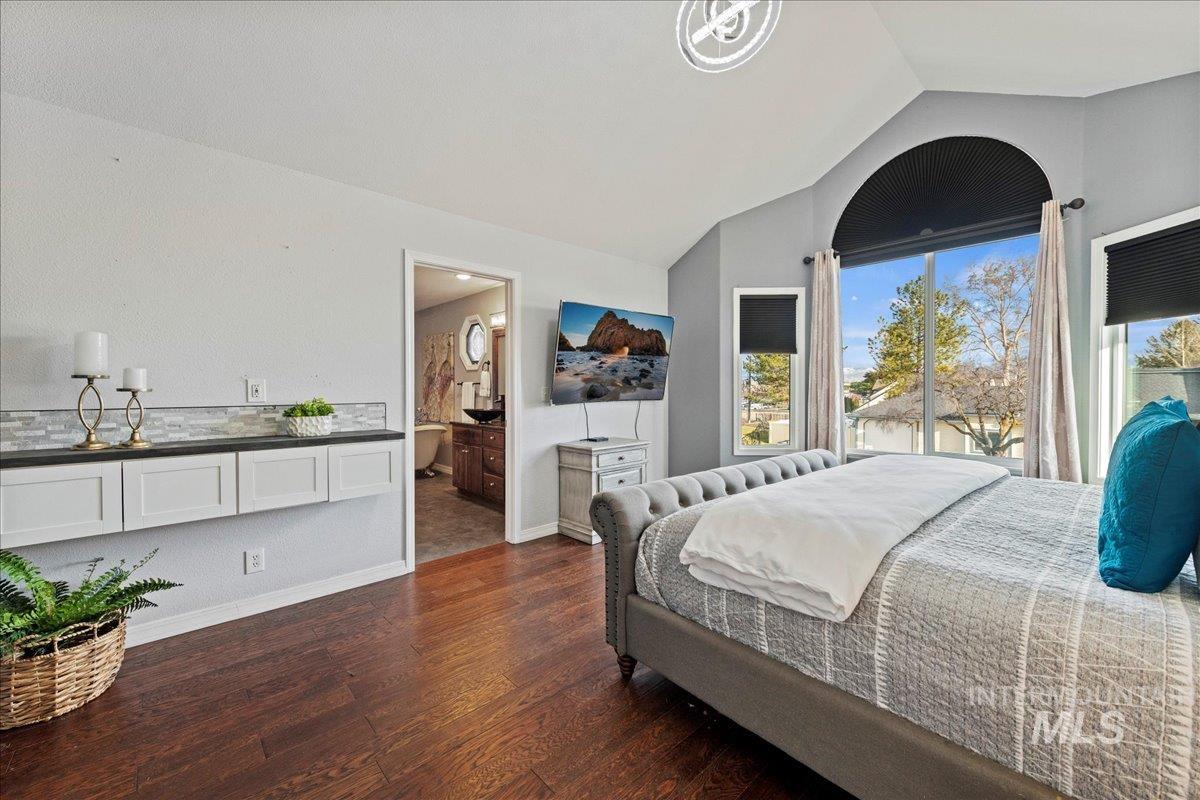 Bedroom with lofted ceiling, dark wood-type flooring, and connected bathroom