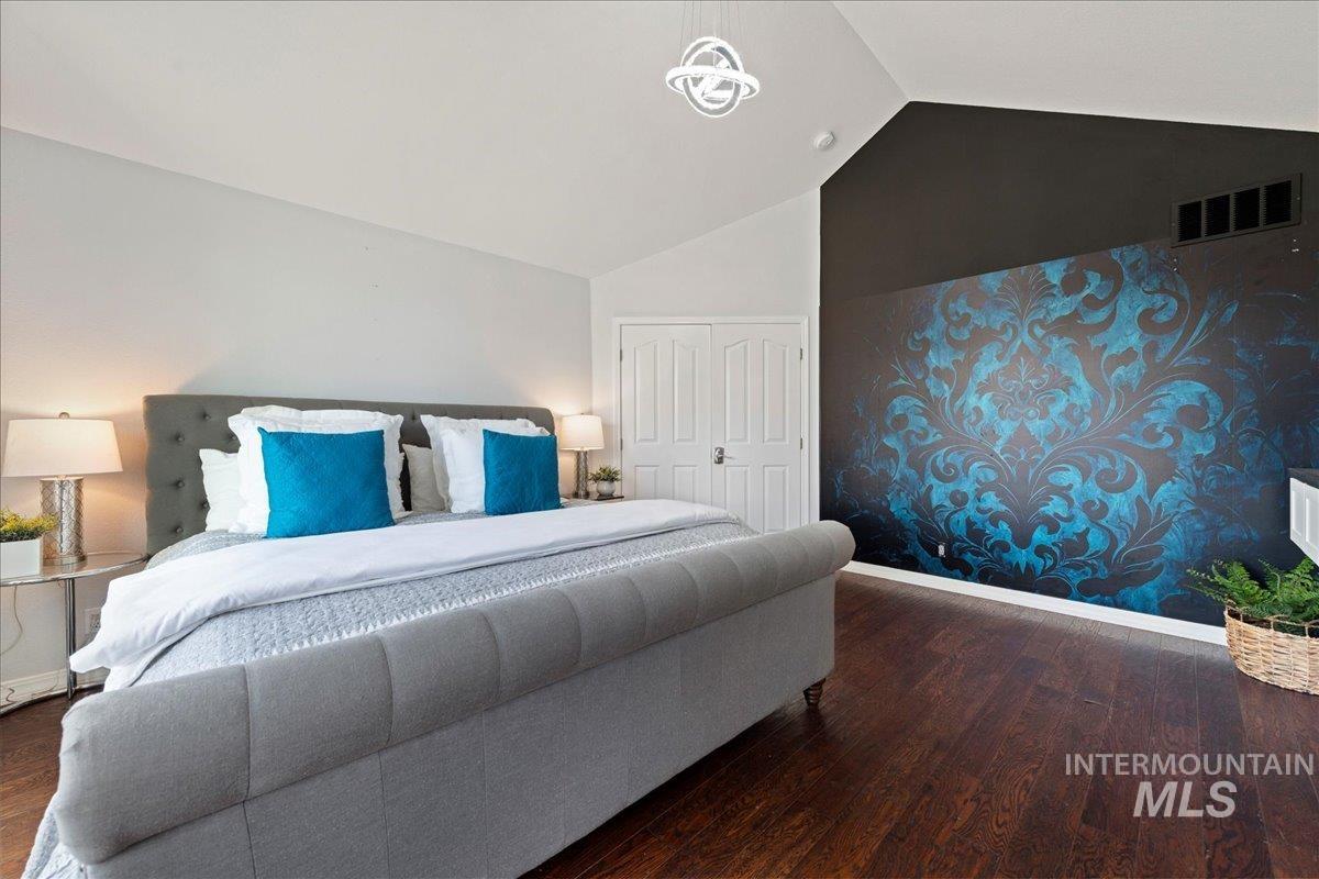 Bedroom featuring vaulted ceiling, dark wood-type flooring, and a closet