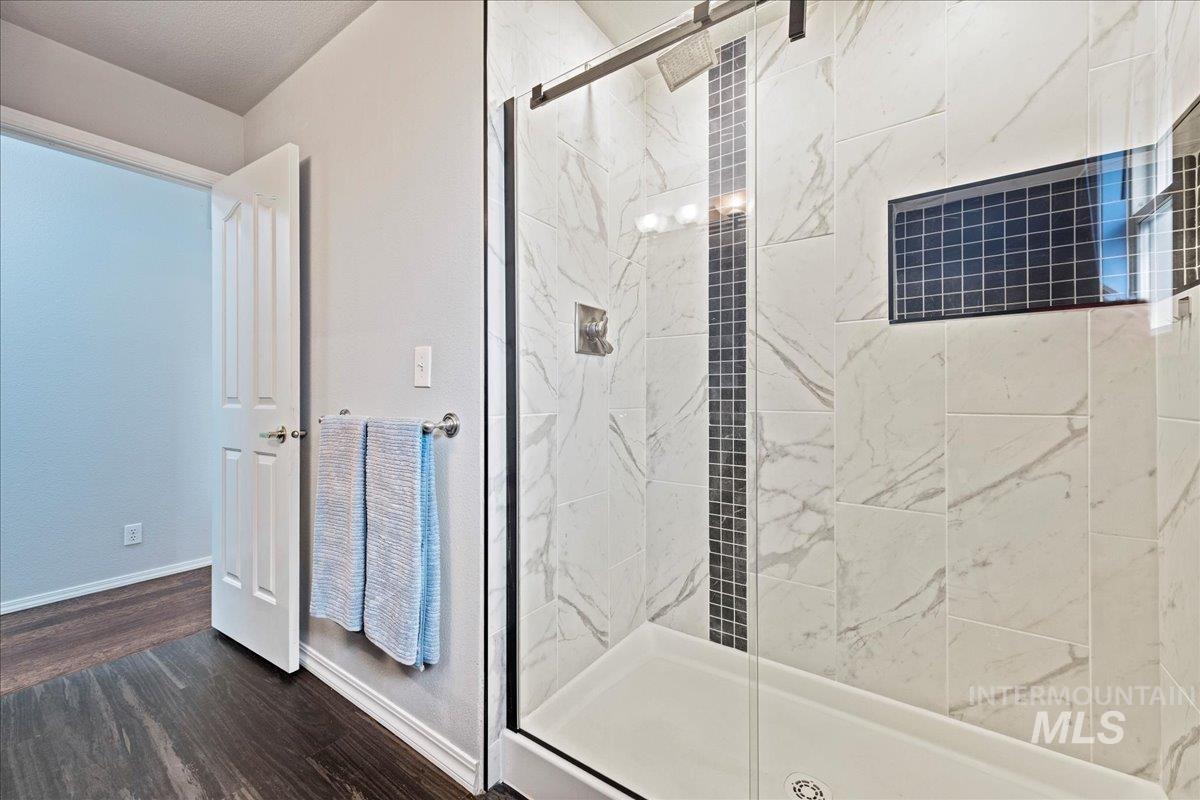 Bathroom featuring a marble finish shower and dark wood-style flooring