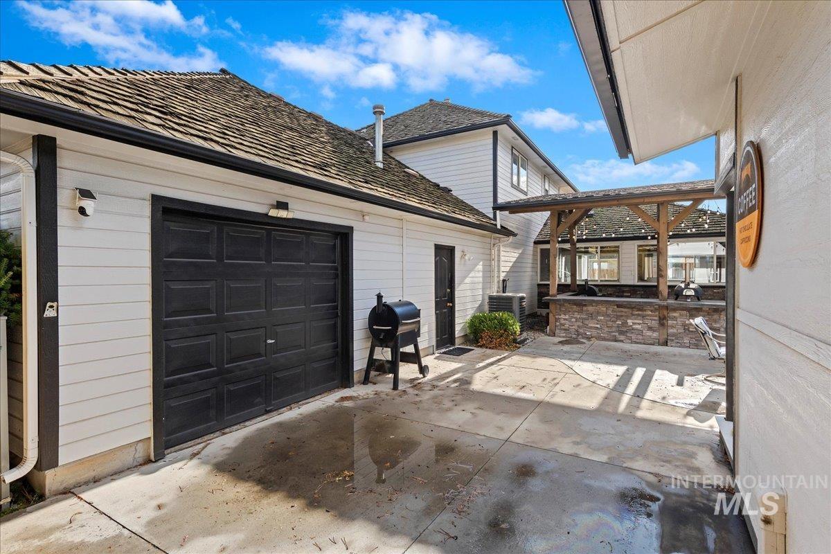 View of property exterior with a patio area, an attached garage, and driveway