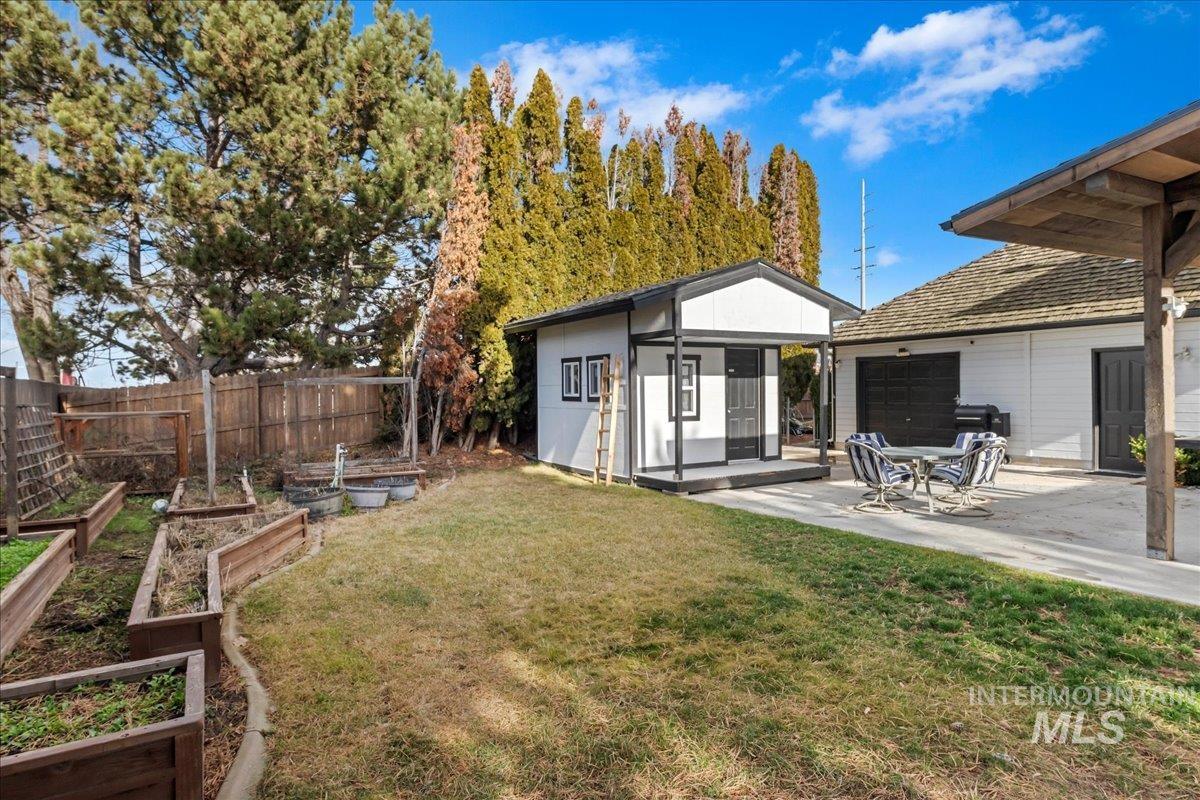 Rear view of property with an outbuilding, a garden, and a patio