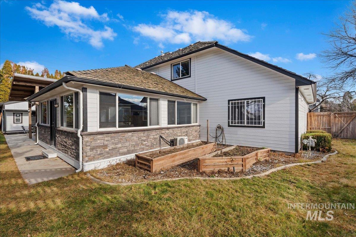 Rear view of property featuring a garden, stone siding, and a sunroom