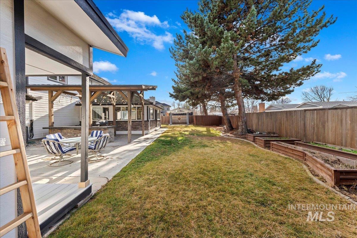 Fenced backyard featuring a vegetable garden and a patio