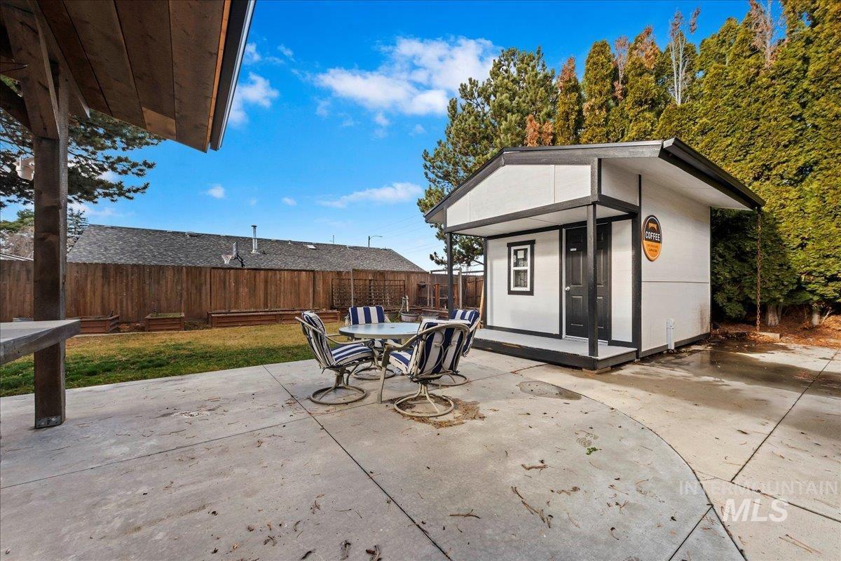 Fenced backyard with a patio area, an outdoor structure, and outdoor dining space